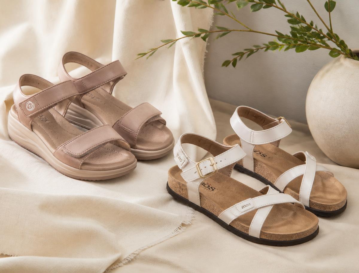 Two pairs of comfort sandals with adjustable straps and cork footbeds on cream fabric